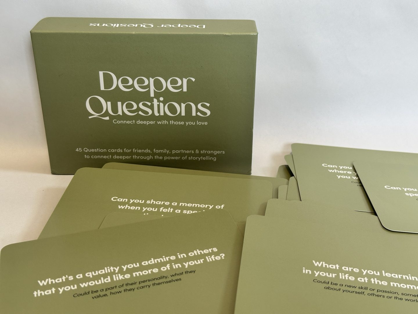 The green Deeper Questions box with question cards spread in front of it.